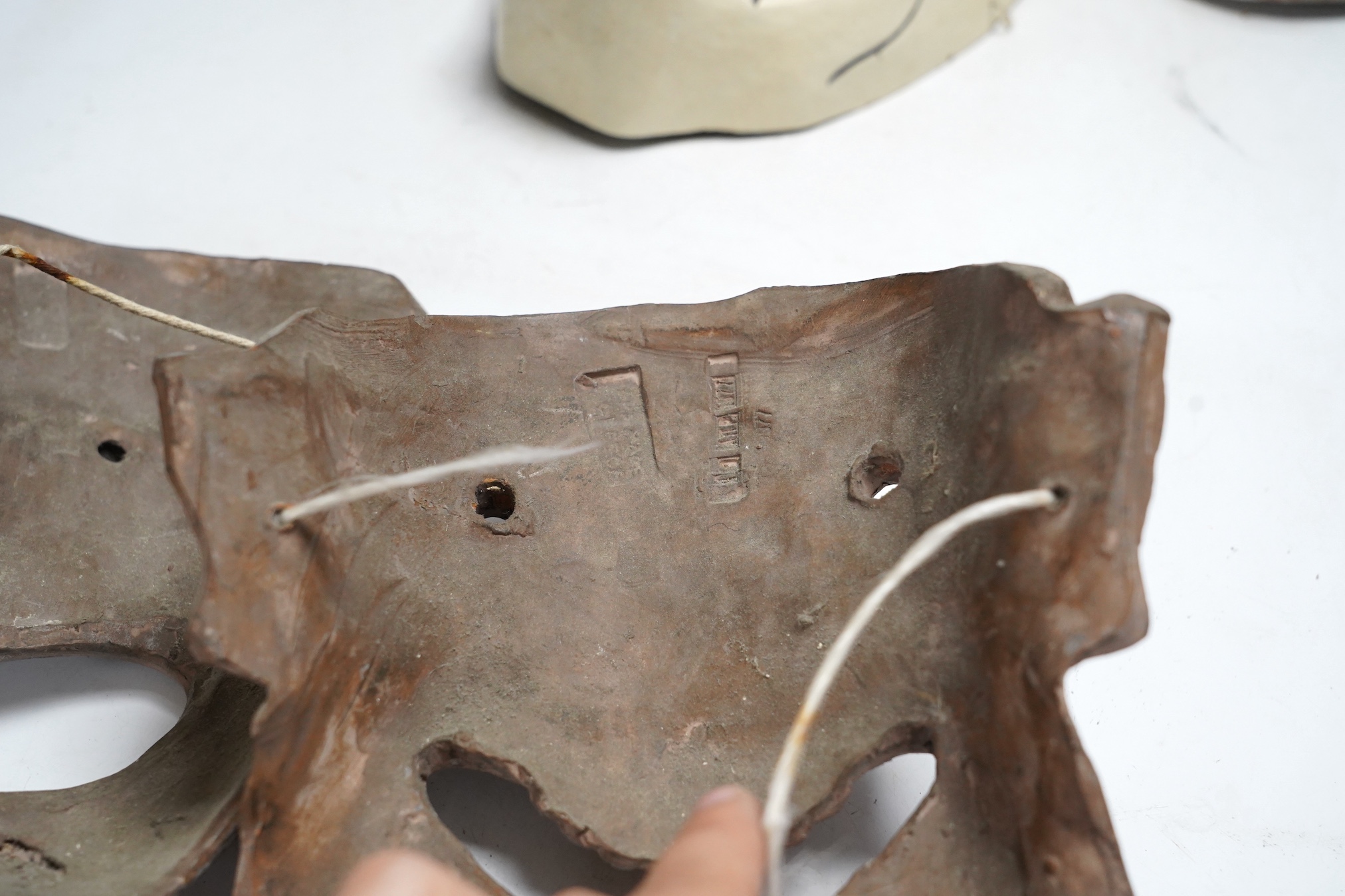 Two pottery face masks, and three pairs of carved and painted masks, largest mask 21cm high